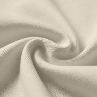 Soft beige fabric close-up showing a smooth, heavyweight knit texture with gentle folds and subtle draping.