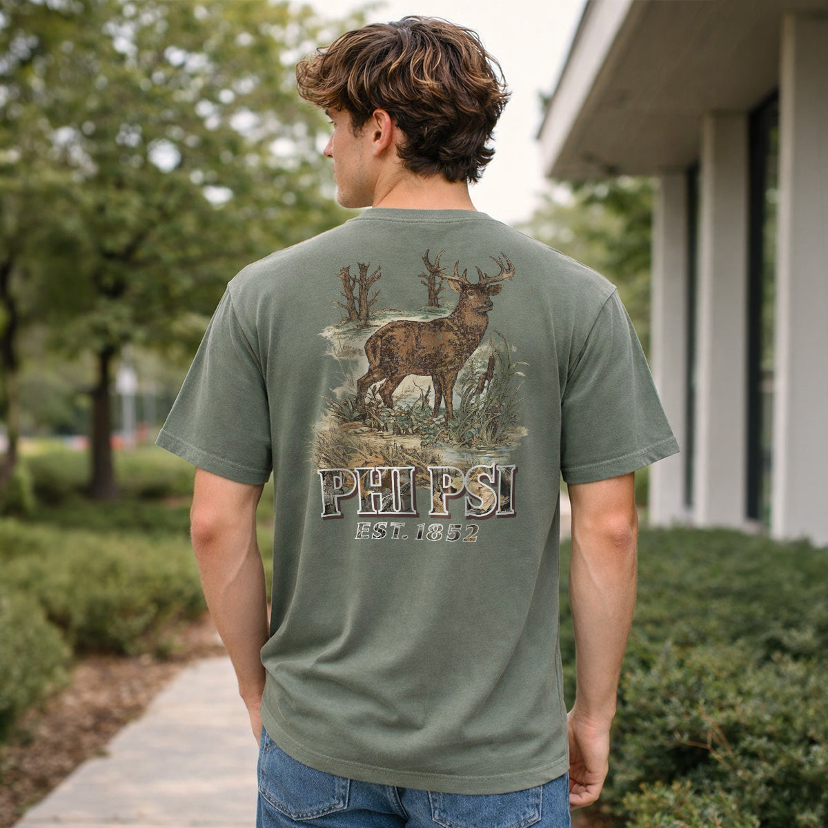 Man wearing a moss green Comfort Colors T-shirt with large woodland deer graphic on the back.