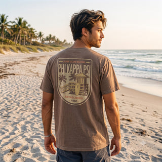 Model wearing the Surf Club Social T-shirt from the back while walking on a beach.