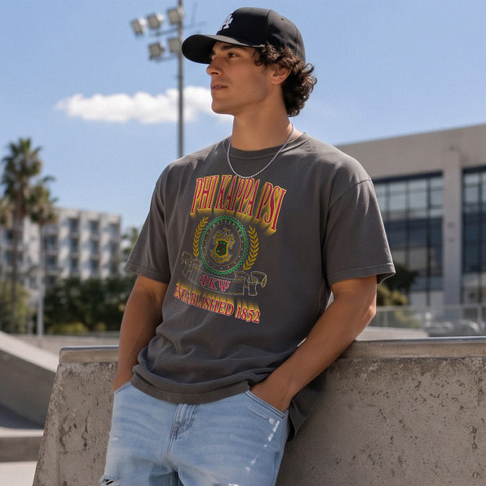 College-aged male wearing the fraternity Collegiate Crest Graphic Tee in charcoal grey, featuring vintage Phi Kappa Psi crest artwork on campus.