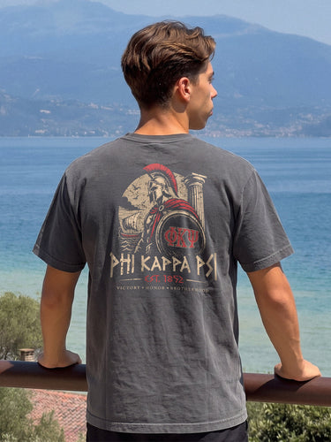 Man wearing a grey comfort colors tee with premium ancient Greece Odyssey design