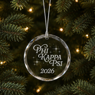 Limited Edition glass Christmas ornament with engraved design hanging on a decorated holiday tree